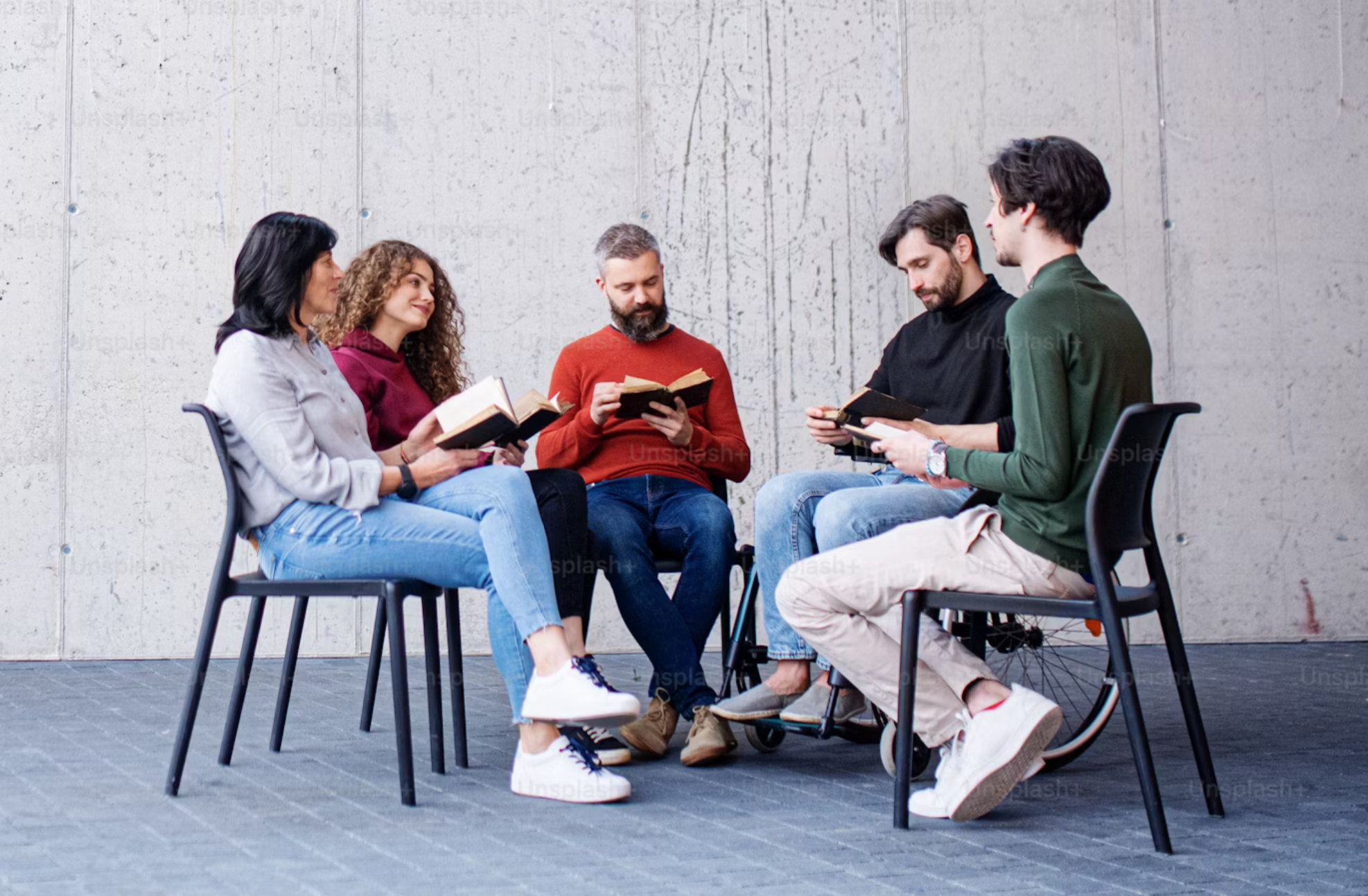 Afbeelding met mensen in een kring, die een boek aan lezen zijn.